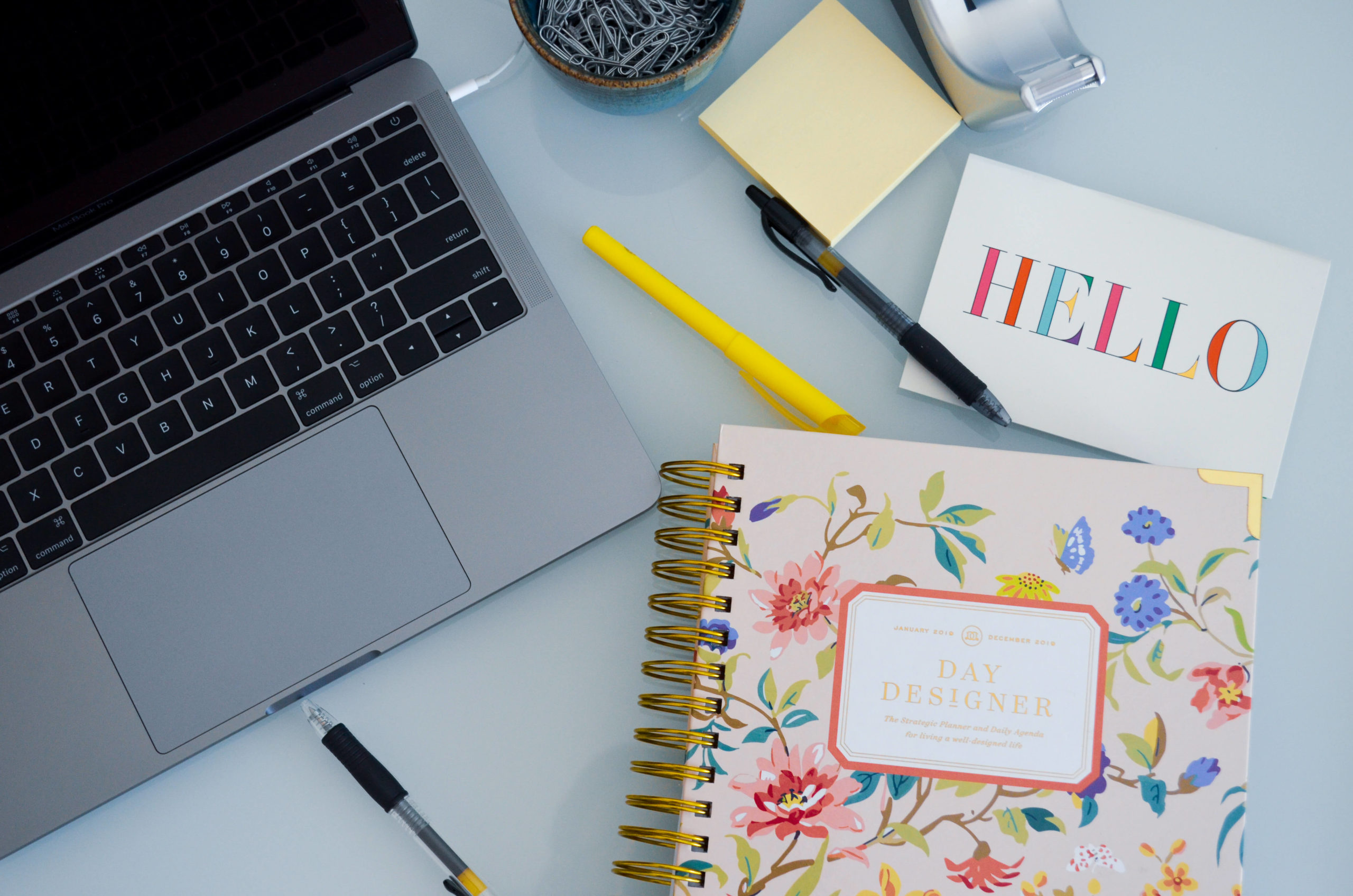 the desk of a creative virtual assistant - notebooks, planners and a computer